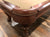 Close-up of a brown leather armchair with intricate design on a wooden floor.