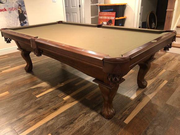 Wooden pool table in a room with signs on the wall