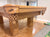 A close-up of a wooden pool table corner with carved details and the Dufferin brand name visible on the pocket flap, set in a home interior with wood floors and a carpeted area.