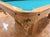 Close-up of a wooden Dufferin pool table corner with turquoise felt and a carved wooden cue pocket, shown on a wood parquet floor.