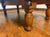 Close-up of a wooden pool table leg with a turned oak finish, set on a polished stone floor.
