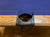 A close-up of a black leather pool cue rest or cup holder attached to a wooden table with a blue felt surface.