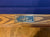 Close-up of a wooden pool table rail with a metal Dufferin Leisure Ltd. brand plaque, set against a blue felt surface.