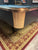 Close-up of a pool table corner with wooden finish on a patterned rug.