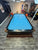 Pool table with blue felt in a room with various toys and furniture.