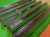 Six polished wooden billiards rails arranged diagonally on a green felt table, with a small metal plaque on one rail.