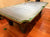 A folding pool table with a green felt surface and dark wooden legs, shown in a room with a polished wood floor.
