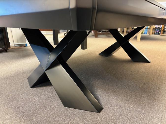 Metallic dining table with X-shaped legs on a carpeted floor.