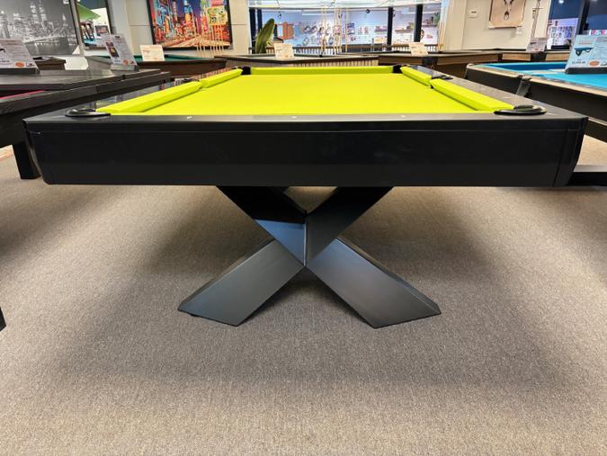 Pool table with a green felt surface in a room with other tables and equipment.