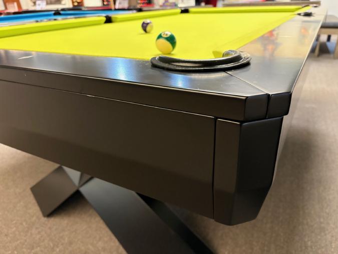 Close-up of a pool table with balls on a bright yellow felt surface.