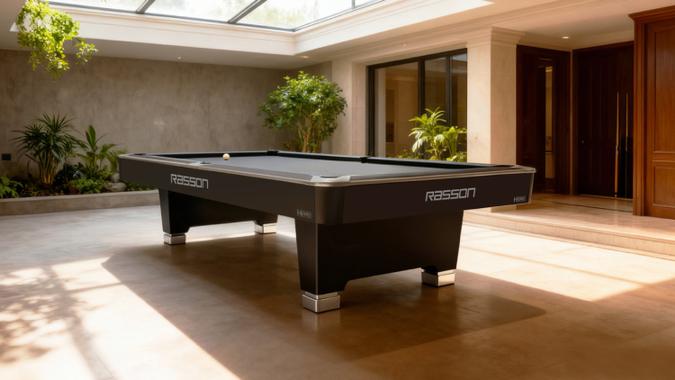 Pool table in a well-lit room with plants and wooden doors.
