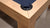 Close-up of a pool table corner with a blue felt surface and wooden frame.