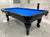 A black 8' Majestic Amboise pool table with blue cloth, featuring a classic design with ornate legs and a sleek finish.