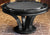 A black finish modern hardwood poker table with a circular shape and a pedestal base.