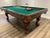 Corner view of the Majestic Pinnacle 7-foot walnut pool table with leather drop pockets, green felt and billiard accessories