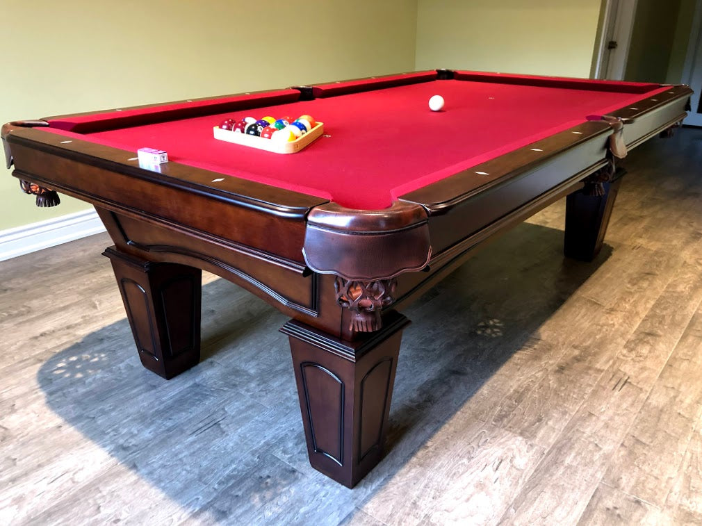Corner view of the Majestic Ascot 7-foot walnut pool table with square legs , red fabric and billiard accessories